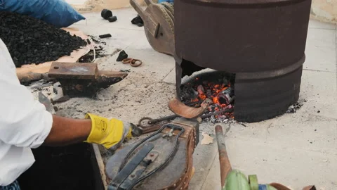 Arabic blacksmith heating rods of metal using charcoal and air blower Vidéo 144413022
