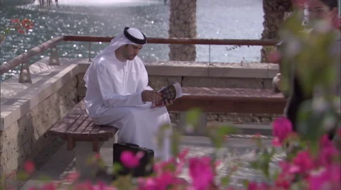 An Arabic businessman sitting on a bench reading a book. Stock Footage 46867784