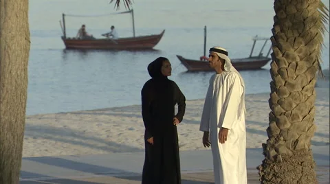 An Arabic couple have a conversation while standing near a beach. Video stock 46865806