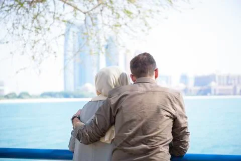 Arabic couple hugs each other by the ocean and looks out Stock Photos
