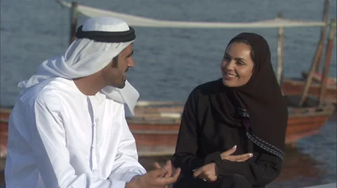 An Arabic couple sit and talk, at the creek in Dubai. Stock Footage 46865686