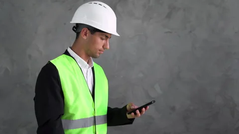 Arabic engineer man with a phone. Builder with smartphone on a grey background Video stock 199251568