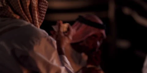 Arabic men drink tea, while sitting around a camp fire in the night. Stock Footage 46870652