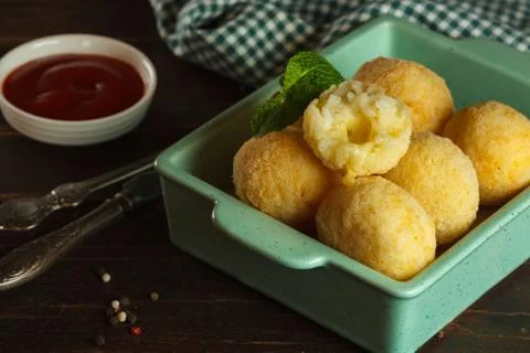 Arancini with mozzarella in a blue rectangular plate, close-up on a dark wooden Stock Photos