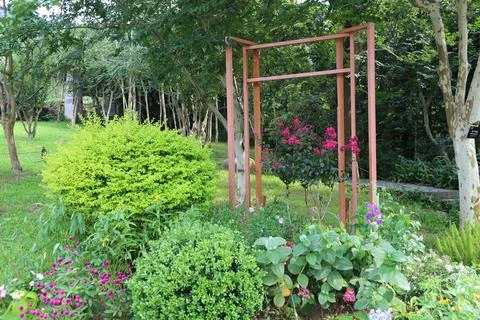 This is an arbor in the middle of a garden, surrounded by various plants an.. Stock Photos