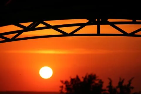 Arc polycarbonate canopy against a setting orange sun Stock-Fotos