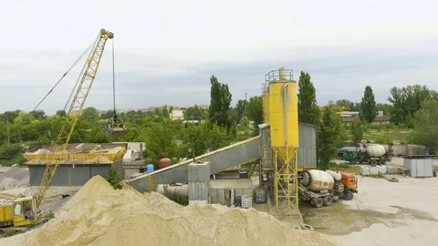 Arc shot of crane claw loading sand into conveyor at concrete factory Stock Footage 106985187