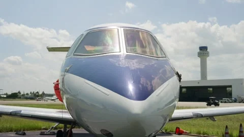 Arc shot of front part of jet Hawker 750 located on tarmac on sunny day. Nose of Stock Footage 254577566