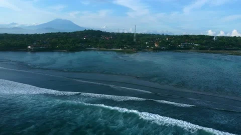 Arc Shot: Waves at Devils Tear with view on Volcano (Bali) Stock Footage 200662228