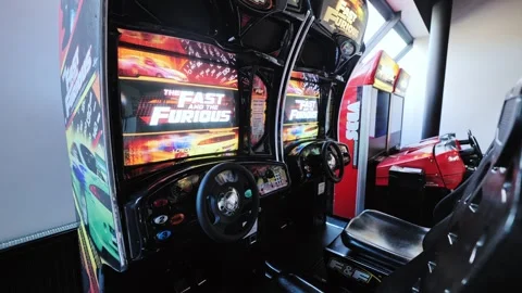 Arcade racing game machines, steering wheels inside modern entertainment center Stock Footage 327774155