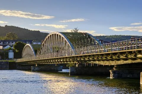 Arch bridge spanning over calm river waters Stock Photos