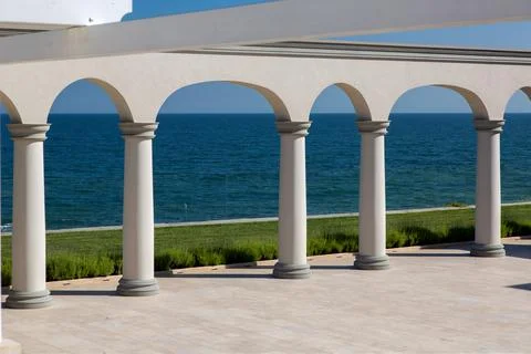 An arch with columns of white stone and a marble floor on sunny day. Stock Photos