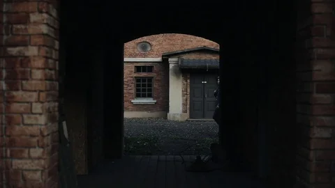 An arch in an old red brick building. A German soldier with a gun going through 库存影片 113948384