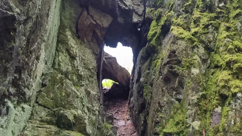 An arch of stones in the rock through which you can see the trees in the forest Stock Footage 242173831