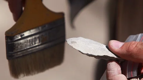 An archaeologist brush off the dust from the artifact at the dig site Stock Footage 124738108