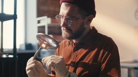 Archaeologist Inspecting Artifact under Magnifying Glass in Laboratory Stock Footage 296515597