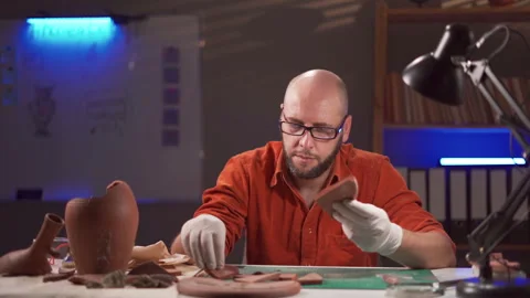 Archaeologist man working in the office late night. Studying artifacts of Stock Footage 251107097