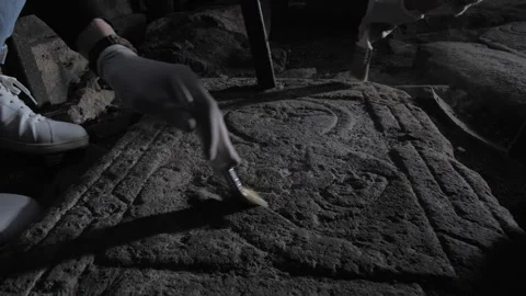 Archaeologists and historians use brushes to sweep away dust from a found carved Vidéo 265677053