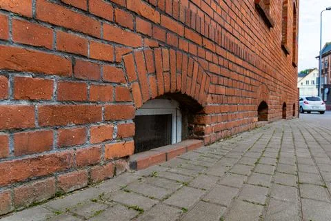 Arched Brick Wall With Basement Window and Cobblestone Sidewalk in a European Stock Photos