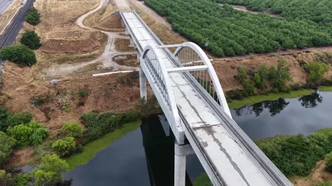 Arched concrete bridge spans quiet river near Fresno, California, USA, forming Stock Footage 339880545