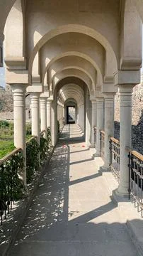 Arched corridor with columns and shadows in a sunny outdoor Stock Photos