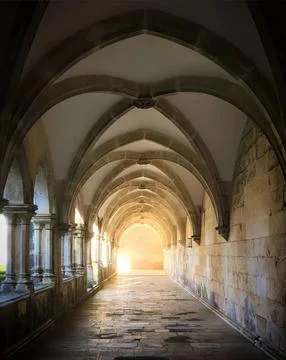 Arched corridor with sunlight shining through at the end Stock Photos