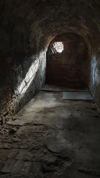 Arched dungeon with light coming from a hole on the wall Stock Photos