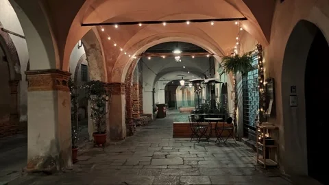 Arched gallery with string lights in an Italian town at night, cozy empty street Stock Footage 330741409