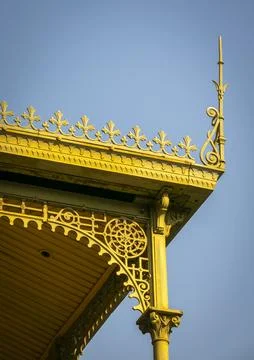 An arched iron bracket with a wheel-shaped rosette frames a corinthian colu.. 스톡 사진