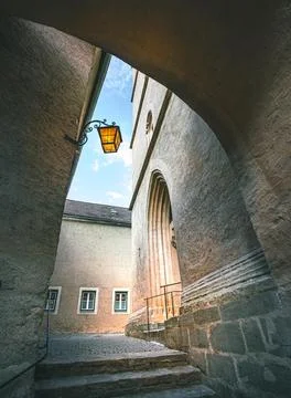 An arched passageway leads to a set of stone steps, with a quaint lantern Stock Photos
