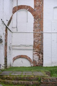 Arched pattern of unpainted brick on the white wall of the medieval Cathedral Stock Photos