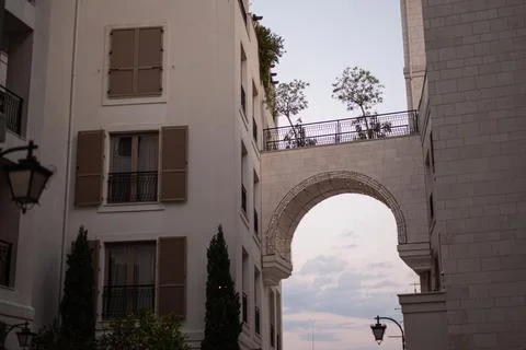 Arched stone bridge connects two residential buildings under twilight sky Stock Photos