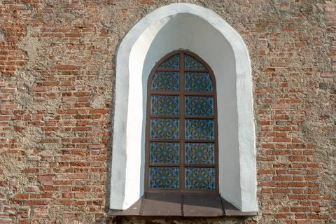 Arched window with bars in the red brick wall. An old building with beautiful Stockfoto's