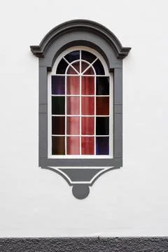 An arched window with a decorative frame divided into several sections with.. Stock Photos