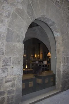 Arched window in a stone castle; reflection of a restaurant in the window Stock Photos