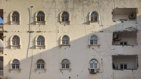 Arched windows on a damaged building facade in sunlight Stock Photos