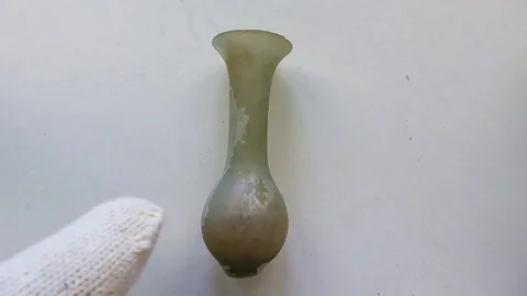 Archeologist inspects ancient small Roman glass scent bottle used for perfume Stock-Footage 79974630