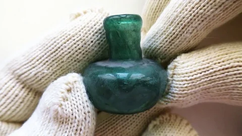 Archeologist inspects ancient small Roman glass scent bottle used for perfume Stock-Footage 79975000