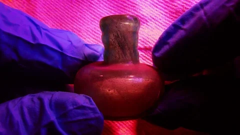 Archeologist inspects ancient small Roman glass scent bottle used for perfume Stock-Footage 80011650