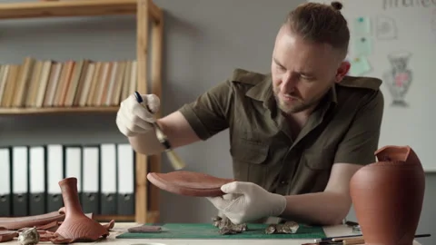 Archeologist working in the office, studying an ancient clay artifacts Stock Footage 251142241