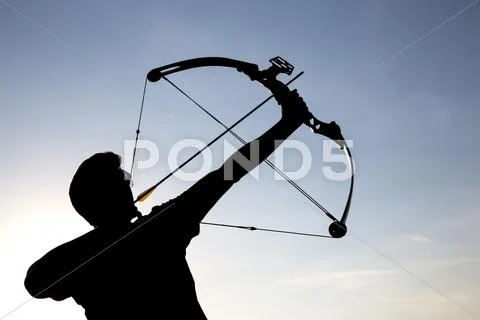 Archer drawing his compound bow silhouette Stock Photos