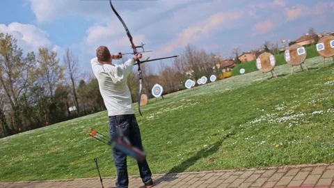 Archer draws bow string and shoots arrow Stock Footage 100558709