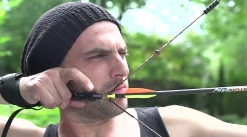 Archer dressed in black, wearing a cap, shooting outdoors, close up. Stock Footage 53857470