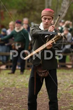 An archer in medieval dress is loading a bolt into a crossbow Stock Photos
