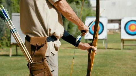 Archery man aiming bow at targets reaching goals Stock Photos