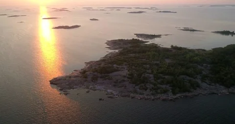 Archipelago sunset, C4K aerial sideway drone view around a rocky bay, the sou Stock Footage 95692302