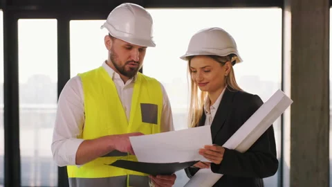 Architect and a builder wearing helmets and construction vests are discussing a Stock Footage 236509639