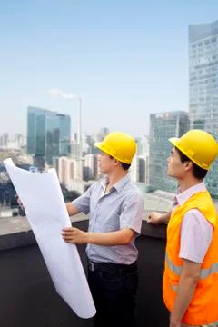 Architect And Construction Worker Talking On Rooftop Foto stock