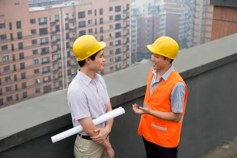 Architect And Construction Worker Talking On Rooftop Stock-Fotos