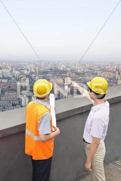 Architect And Construction Worker Talking On Rooftop Stock Photos